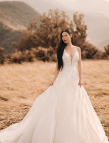 Model wearing a beautiful wedding dress in a meadow high on a mountain.