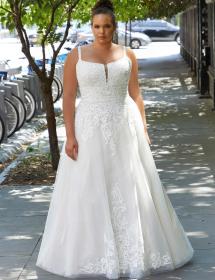 Plus size model wearing a stunning wedding dress in front of a bicycle rack on the left.