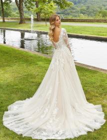 Plus size model wearing a stunning wedding dress on grass in front of a pool with a fountain.
