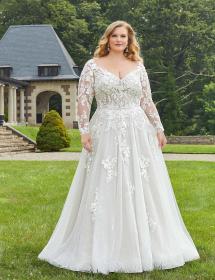 Plus size model wearing a stunning wedding dress with a house in the background.