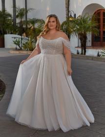 Plus size model wearing a stunning wedding dress in front of cactus gardens.