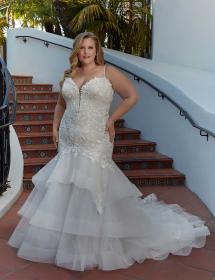 Plus size model wearing a stunning wedding dress in front of a winding staircase