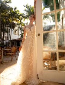 Model wearing a wedding dress in leaning on an open window door.