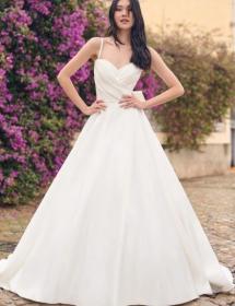 With a big flower bush in the background, an exquisite bride is modeling a wedding gown