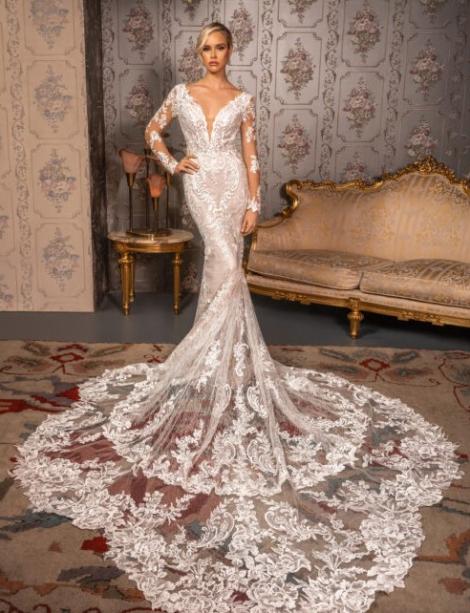 Fancy schmancy wedding dress worn by a woman in front of an elegant sofa and wall