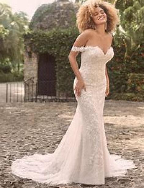 Plus size woman with big hair wearing a bridal gown in posh outside surroundings