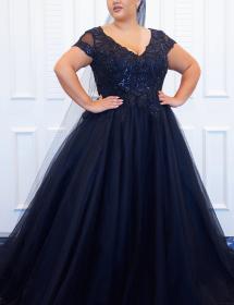 Plus size model wearing a beautiful black wedding dress in front of white wooden panels.