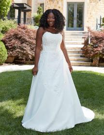 Plus size Black model wearing a beautiful wedding dress on a grassy area in front of a nice home.