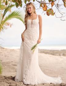 Model wearing a beautiful wedding dress on a beach with palms in the immediate background.