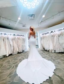 Model in the middle of Pittsburgh bridal salon MB Bride modeling a Maja Bella gown with a very long train.