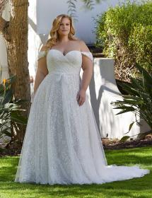 Plus size model modeling the back of an exquisite wedding dress in front of a creme colored curtain.