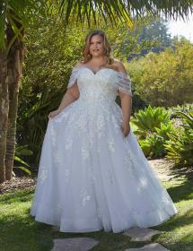Plus size model wearing a beautiful wedding dress in front of a garden of cactus and palms.