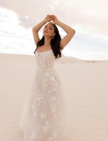 Model wearing a wedding dress in a desert of white sand.