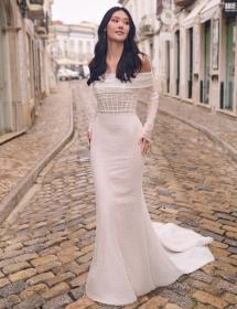 Model wearing a wedding dres the middle of a narrow cobblestone street trying not to be hit by cars.