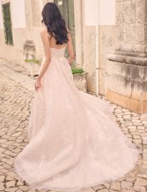 Plus size model wearing a beautiful wedding dress in front of a stained wall.