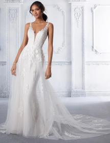 Model wearing a wedding dress in front of highly molded white walls.