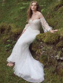 Model wearing a wedding dress leaning on an earth embankment