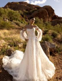 Model wearing a wedding dress in a very dry looking desert.