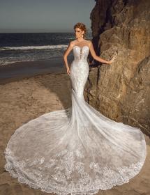 Happy model wearing a wedding gown in front of a beach cliff.
